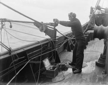 A sailor listening on a hydrophone on board a British armed trawler.